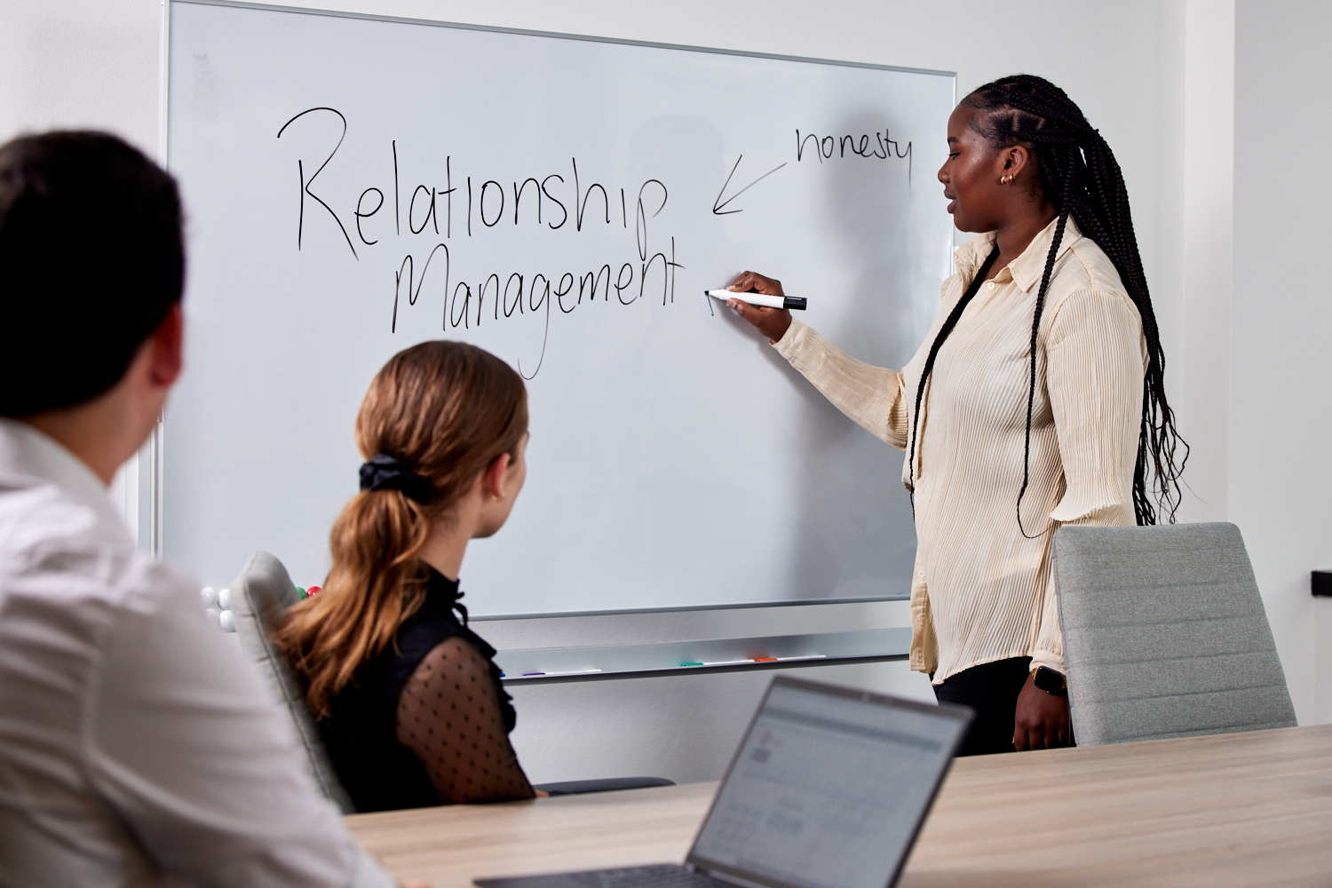 Supervisor writing on whiteboard talking to the team about managing relationships with participants