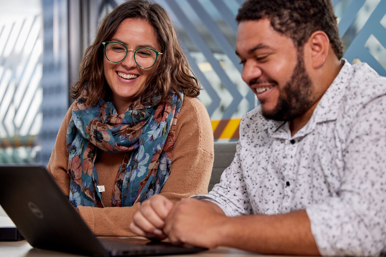 Learning and development manager and worker looking at a laptop talking about how the provider will support staff to grow their skills
