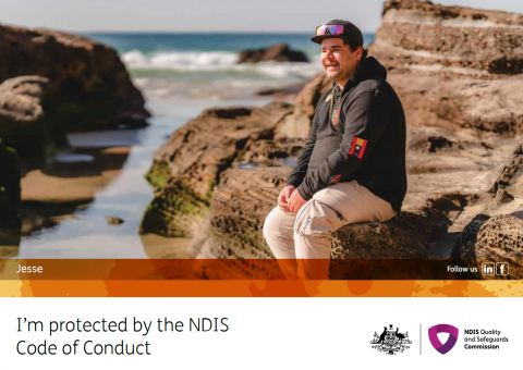 A code of conduct postcard featuring Jesse. Jesse is sitting on rocks at the beach. He is wearing beige pants and a black hoodie with a black baseball cap. He is looking away from the camera and smiling.